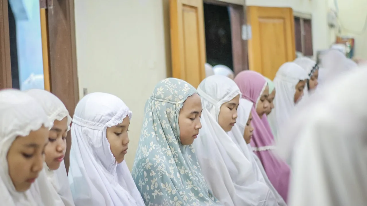 Para santri mengenakan mukena dalam kegiatan ibadah bersama